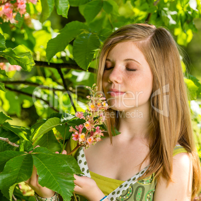Young girl smelling blossom of the tree