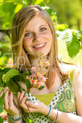 Teenage girl smelling blooming tree in springtime