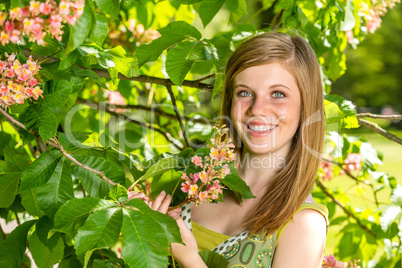 Young girl holding blossom in sunny park