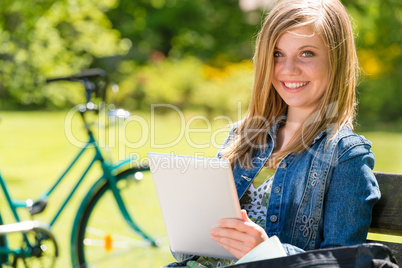 Adolescent girl using tablet computer in park