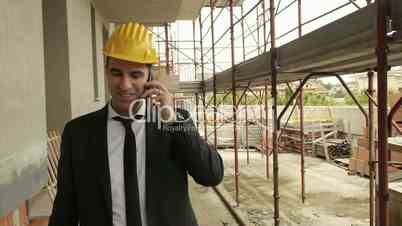 Engineer talking on mobile phone and walking in construction site