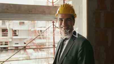 Engineer with helmet in construction site smiling at camera, portrait