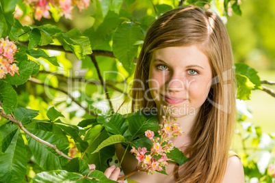 Girl in the sunshine smelling tree blossom