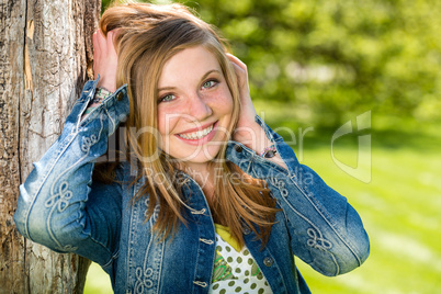 Overjoyed girl outside leaning to tree