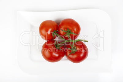 Vier Tomaten auf einem Teller