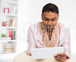 Indian man using digital tablet pc at home.