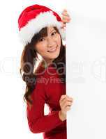 Christmas girl peeking from behind blank sign billboard.