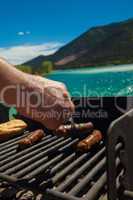 man cooking sausages over a barbecue