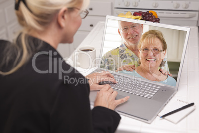 Woman In Kitchen Using Laptop - Online with Senior Couple
