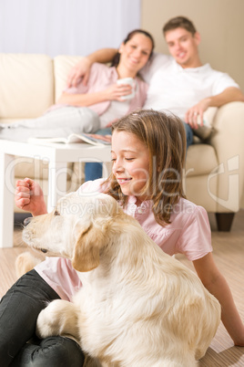 Playful girl petting family dog with parents