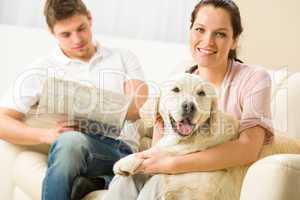 Resting joyful couple sitting and petting dog