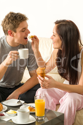 Carefree couple eating breakfast in pajamas