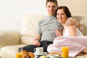Cheerful couple sitting on couch before breakfast
