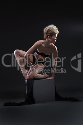 Elegant curly blonde posing on cube