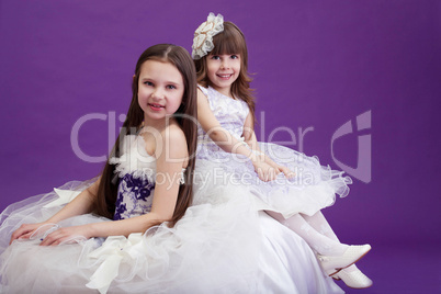 Two smiling little girls posing in elegant dresses