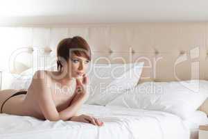 Portrait of young topless woman posing in bed