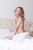Lovely nude woman sitting on hotel bed