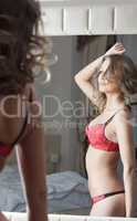 Sexy brunette posing in red lingerie near mirror