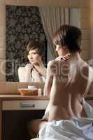 Slim nude woman posing near mirror