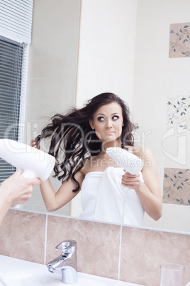 Reflection of pretty woman drying hair