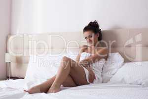 Smiling young woman posing on hotel bed