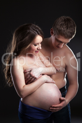 Young man caresses pregnant woman's belly