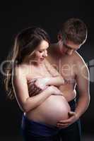 Young man caresses pregnant woman's belly
