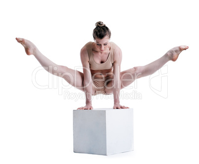 Young pretty acrobat posing with cube in studio