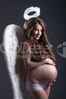 Young pregnant woman in angel costume