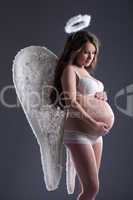 Pretty pregnant woman posing in angel costume