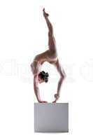 Slim woman balancing on cube in studio