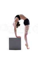 Pretty flexible girl posing on cube in studio