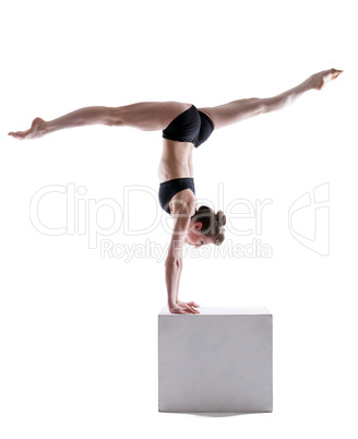Flexible gymnast balancing on cube in studio