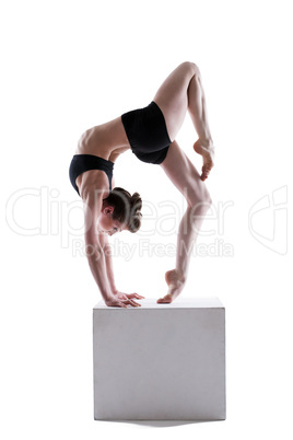 Attractive young woman posing on cube in studio