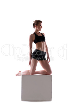 Young athletic brunette posing on cube