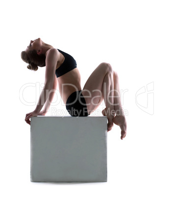 Beautiful woman posing on cube in studio