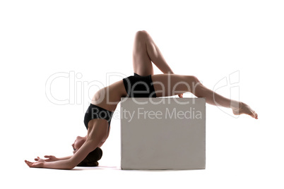 Young slim woman posing on cube in studio