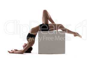 Young slim woman posing on cube in studio