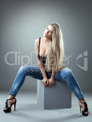 Spectacular blonde posing on cube in studio
