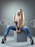 Spectacular blonde posing on cube in studio