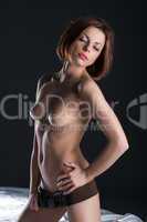 Seductive topless brunette posing in leather belt