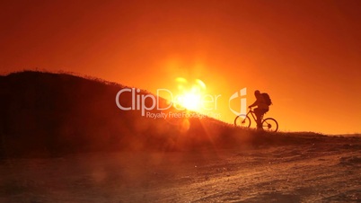 Cyclist riding bicycle into the rising sun