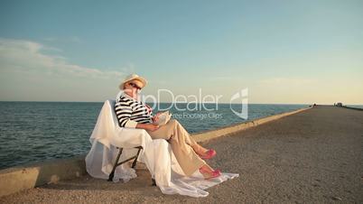 Retired woman relaxing with book at seaside
