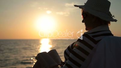 Senior lady silhouette by the sea at sunset