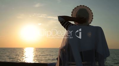 Senior woman silhouette by sea at sunset