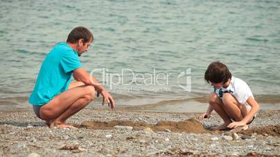 Child and father playing on the summer beach