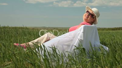 Happy senior woman relaxing on a green meadow