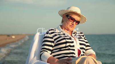 Senior lady relaxing on  the seacoast at sunset