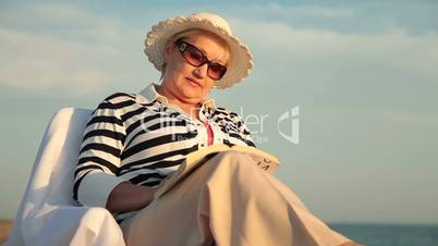 Elderly woman with book at the seaside