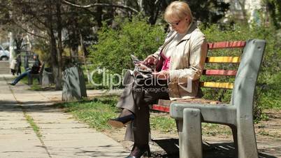 Senior Woman Reading Magazine In The Park